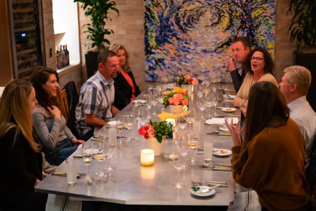 A group of people laughing in the bouchon Cork Room dining room